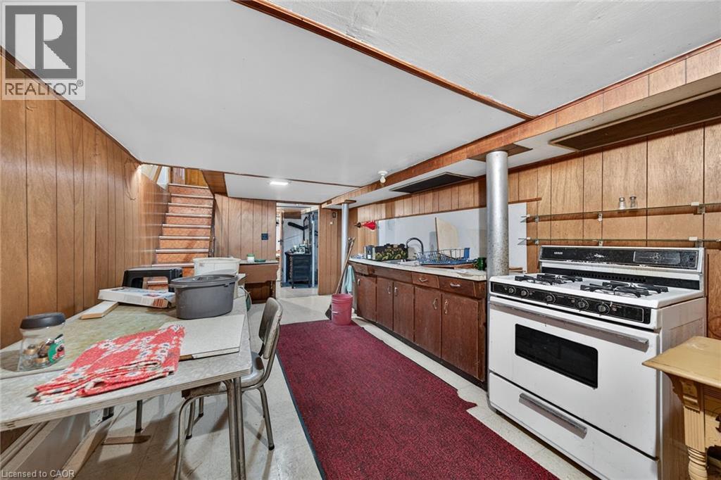 Basement space featuring wood-finish paneling, an exposed beam ceiling, a full-size range, and a sink with lower cabinetry - 16 Mulberry Street, Hamilton, ON