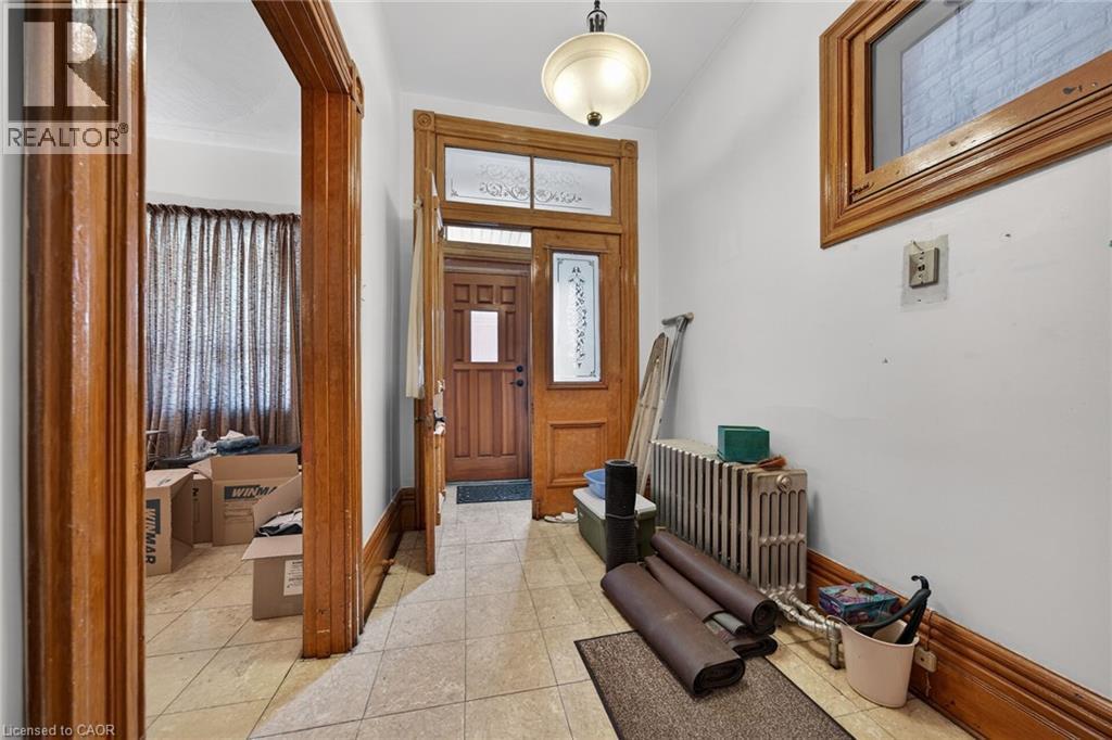 Entryway featuring light-toned tile flooring and a wood-paneled door with decorative glass inserts - 16 Mulberry Street, Hamilton, ON