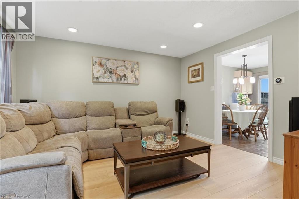 Recessed lighting illuminates the living area featuring light wood-finish flooring and a wide doorway to the dining space - 116 Scott Road, Cambridge, ON