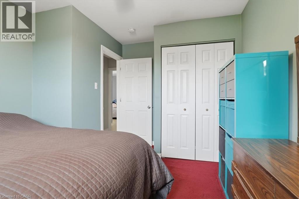 Interior room featuring light green walls, a red carpeted floor, and white bi-fold closet doors - 116 Scott Road, Cambridge, ON