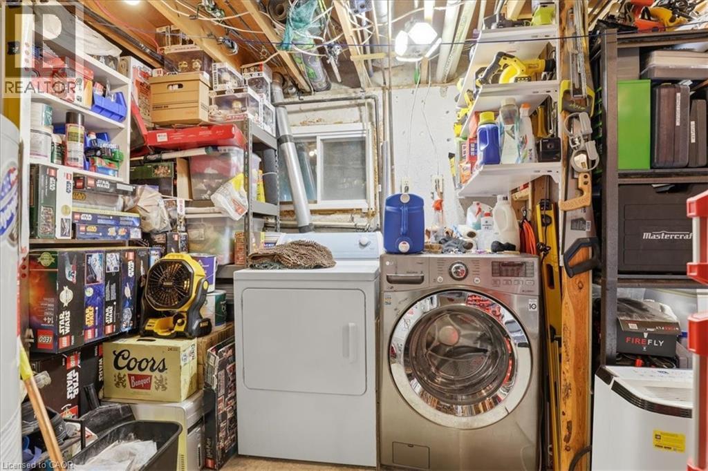 Laundry area featuring a front-loading washing machine, a white dryer, and exposed ceiling joists - 116 Scott Road, Cambridge, ON