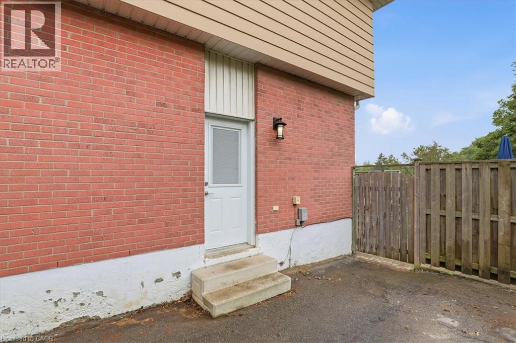 Brick exterior featuring a white entry door with an integrated screen, concrete steps, and an exterior wall light fixture - 116 Scott Road, Cambridge, ON