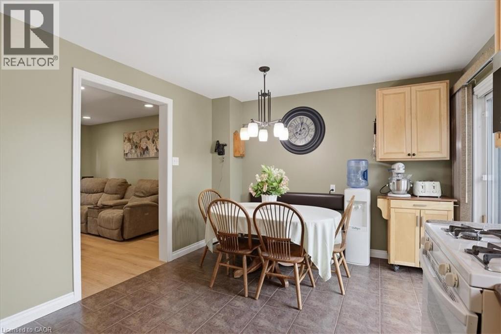 Dining area featuring a contemporary chandelier, built-in banquette seating, and tiled flooring - 116 Scott Road, Cambridge, ON