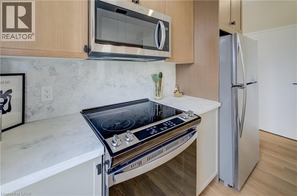 Kitchen featuring stainless steel appliances, light wood-finish cabinetry, a smooth-top electric range, a built-in microwave, and light-toned countertops with a matching backsplash - 210 Heritage Drive Unit# Upper, Kitchener, ON