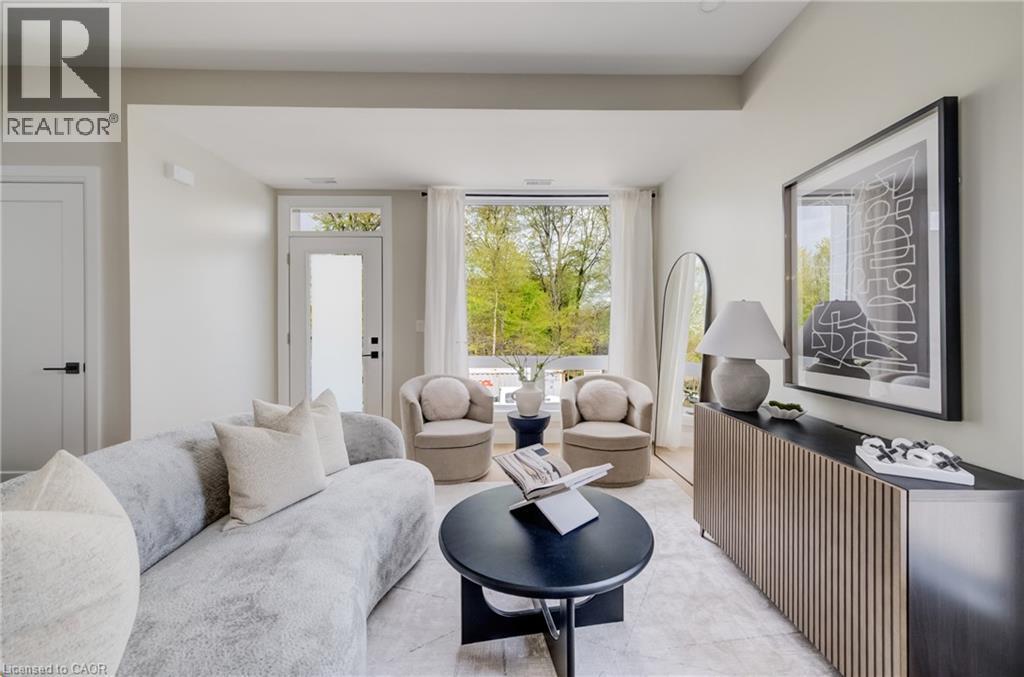 Living space featuring abundant natural light, a full-lite glass door, and large windows showcasing tree-lined surroundings - 210 Heritage Drive Unit# Upper, Kitchener, ON