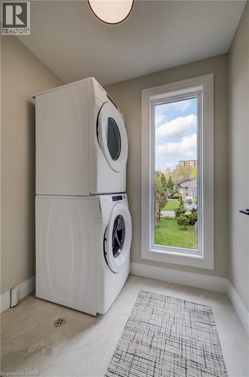 Laundry area with stacked appliances, a single window, light-toned wall paint, and tile flooring - 210 Heritage Drive Unit# Upper, Kitchener, ON