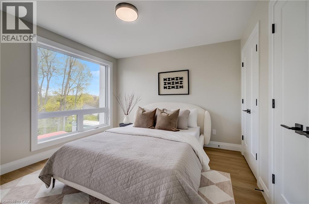 Bedroom featuring wood-finish flooring, a contemporary window, and two paneled doors with matte black hardware - 210 Heritage Drive Unit# Upper, Kitchener, ON