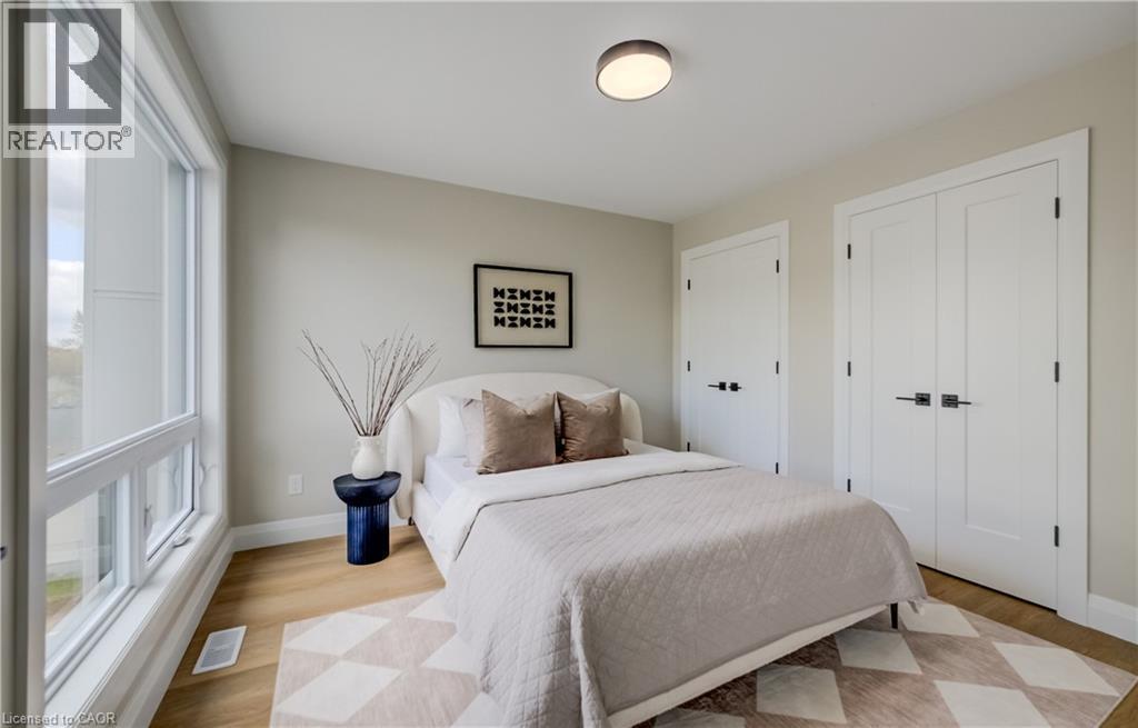 Light-filled interior featuring expansive windows, wood-finish flooring, two panel doors with matte black hardware, and a modern flush-mount ceiling light - 210 Heritage Drive Unit# Upper, Kitchener, ON