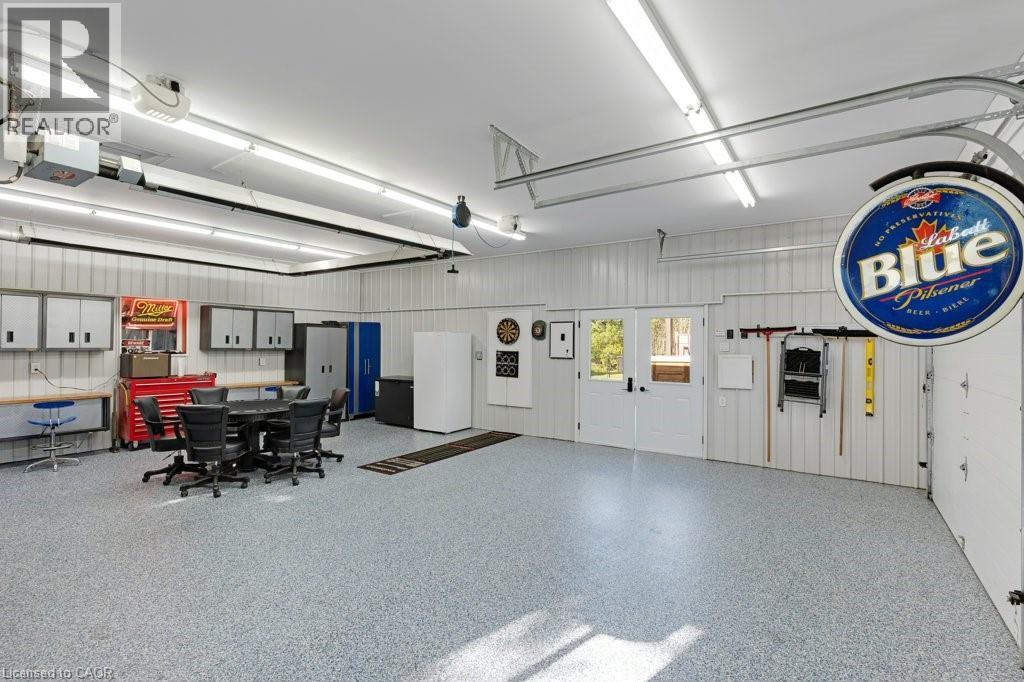 Spacious garage featuring a durable epoxy floor, ample overhead lighting, double exterior doors, and corrugated panel walls - 3786 Old Beverly Road, North Dumfries, ON