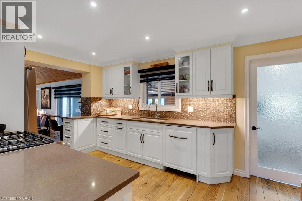 Kitchen featuring white Shaker-style cabinetry, wood-finish flooring, a mosaic tile backsplash, recessed lighting, and a built-in gas range - 3786 Old Beverly Road, North Dumfries, ON
