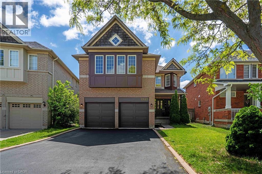 Brick and siding exterior featuring a prominent bay window with multiple panes, a diamond-shaped window in the gable, and a two-car garage with dark-toned doors - 2425 Nichols Drive, Oakville, ON - Outdoor With Facade
