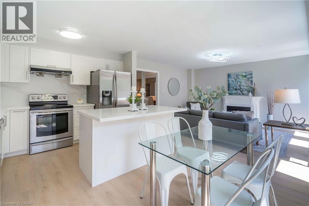 Open-concept living area featuring a modern kitchen with white cabinetry, stainless steel appliances, and light wood-finish flooring - 2425 Nichols Drive, Oakville, ON - Indoor Photo Showing Kitchen With Stainless Steel Kitchen With Upgraded Kitchen