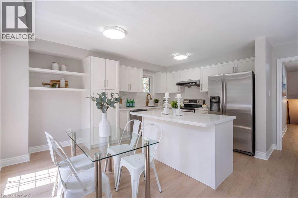 Bright kitchen featuring white cabinetry, a central island with a solid surface countertop, stainless steel appliances, and integrated shelving - 2425 Nichols Drive, Oakville, ON - Indoor