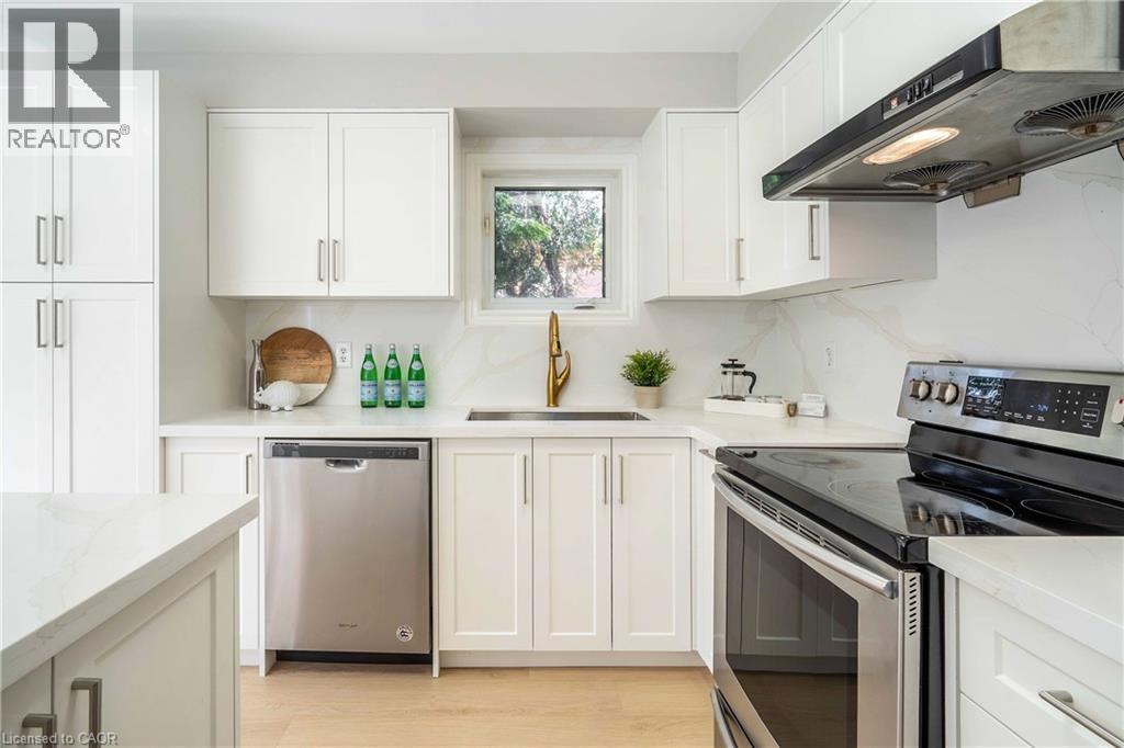 Modern kitchen featuring white shaker cabinetry, stainless steel appliances, a brass-finish faucet, white countertops, and wood-finish flooring - 2425 Nichols Drive, Oakville, ON - Indoor Photo Showing Kitchen With Stainless Steel Kitchen