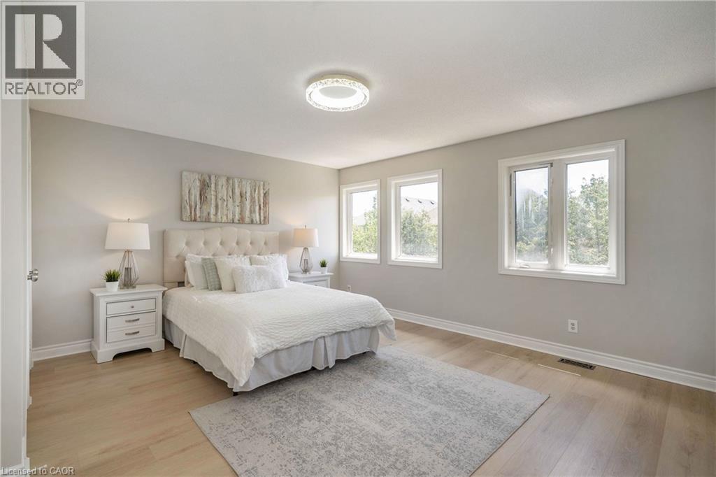 Spacious room featuring light wood-finish flooring and multiple windows with white trim - 2425 Nichols Drive, Oakville, ON - Indoor Photo Showing Bedroom