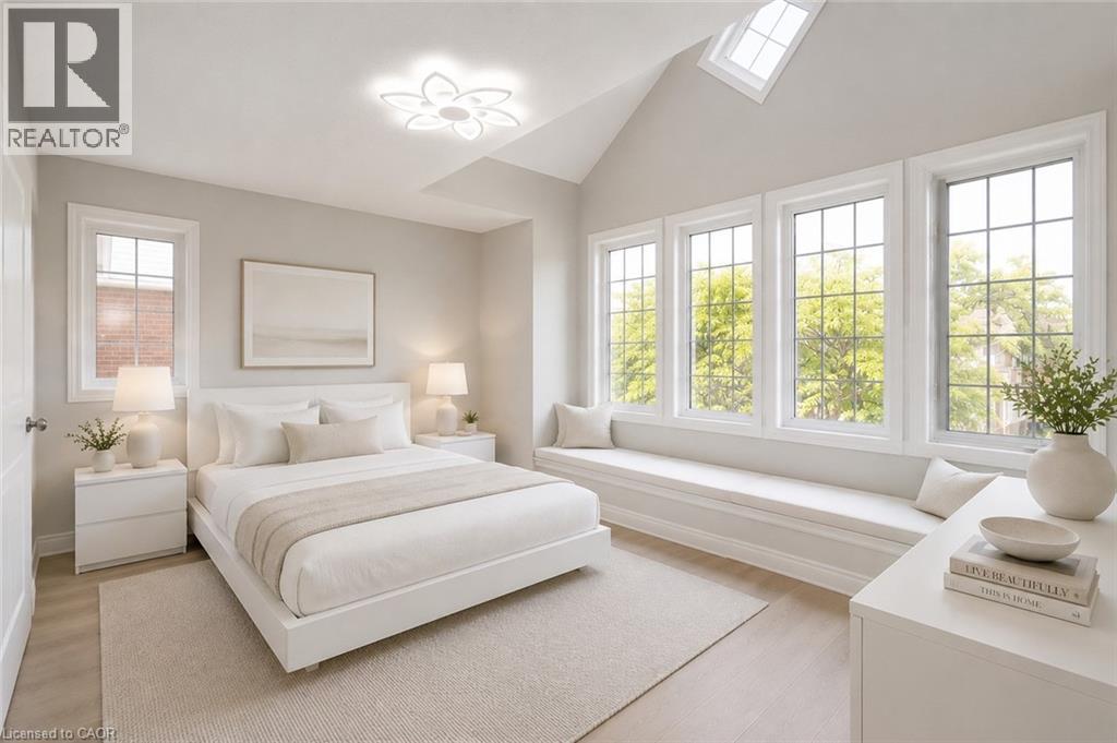 Vaulted ceiling room featuring a wall of multiple pane windows, a built-in window seat, a ceiling-mounted light fixture, and light-tone wood-finish flooring - 2425 Nichols Drive, Oakville, ON - Indoor Photo Showing Bedroom