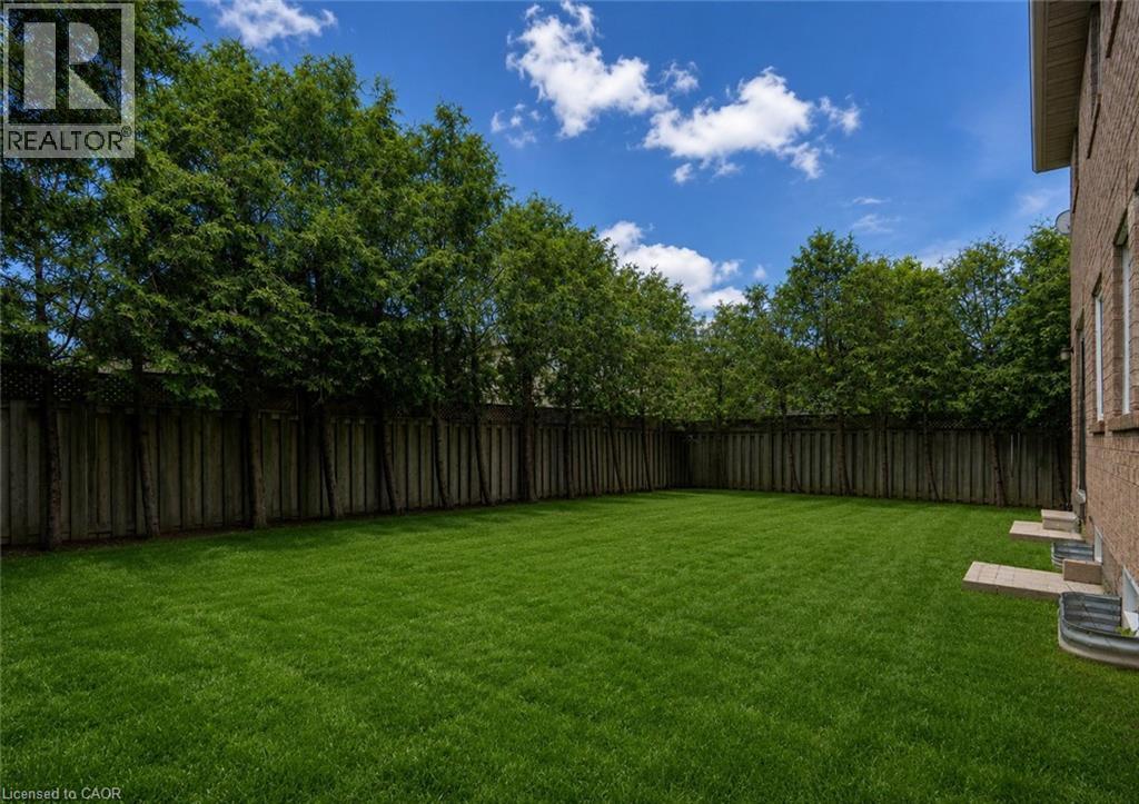 Expansive grass lawn bordered by a wood fence and mature trees - 2425 Nichols Drive, Oakville, ON - Outdoor