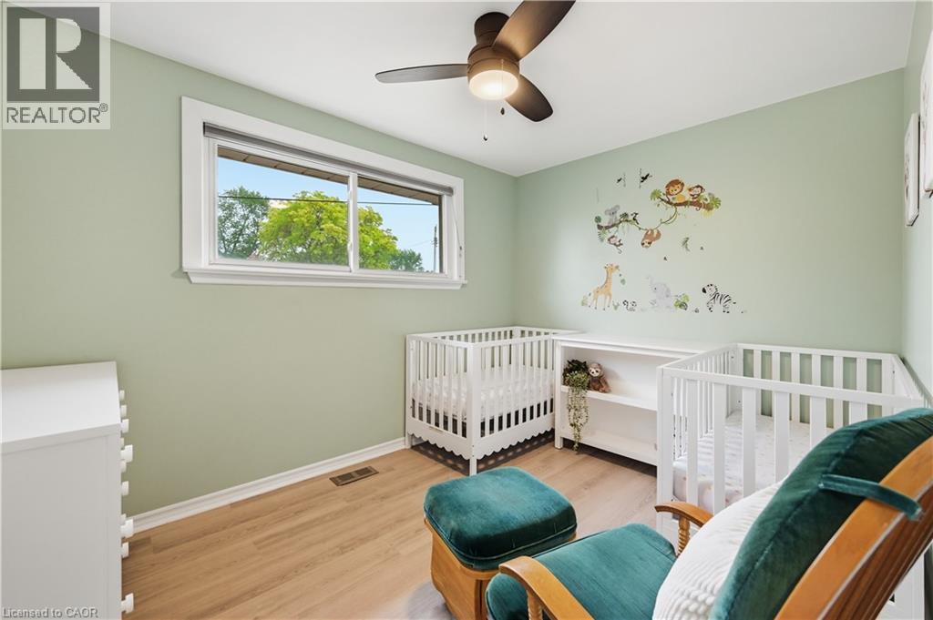 Room featuring a window with white trim, wood-finish flooring, and light green walls - 189 Foxbar Road, Burlington, ON