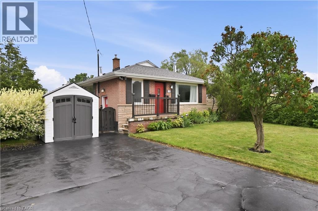 Brick bungalow with a black asphalt driveway, a detached storage shed, a manicured lawn, and mature landscaping - 189 Foxbar Road, Burlington, ON