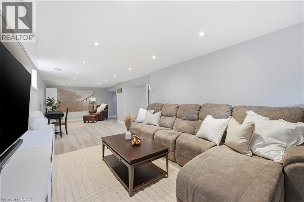 Spacious recreation room featuring recessed lighting, light-toned wood-finish flooring, a neutral color palette, a media wall with built-in cabinetry, and an additional seating area - 189 Foxbar Road, Burlington, ON