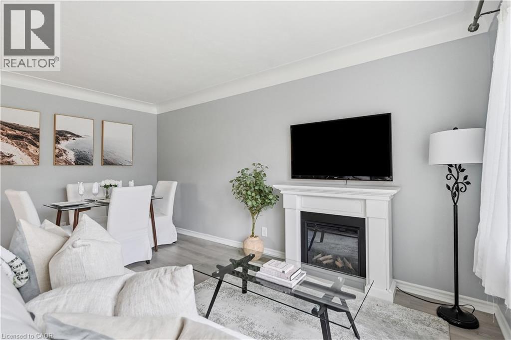 Living area featuring a white mantel, an integrated fireplace, and wood-finish flooring - 189 Foxbar Road, Burlington, ON