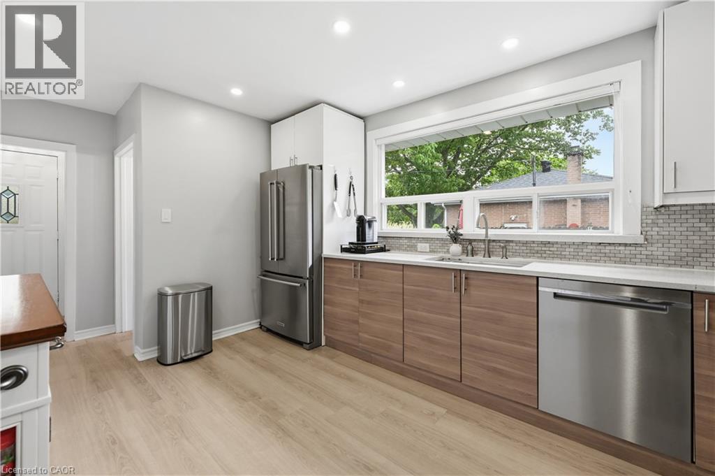 Kitchen featuring wood-finish lower cabinetry, white upper cabinetry, and light-toned countertops - 189 Foxbar Road, Burlington, ON