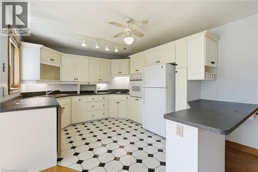 Spacious kitchen featuring extensive cream-colored cabinetry, dark countertops, and a striking black and white hexagonal tile floor - 3 Ancaster Street E, Dundas, ON - Indoor Photo Showing Kitchen