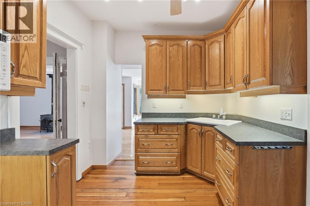 Kitchen featuring wood cabinetry, laminate countertops, a white sink, and wood-finish flooring - 3 Ancaster Street E, Dundas, ON - Indoor Photo Showing Kitchen