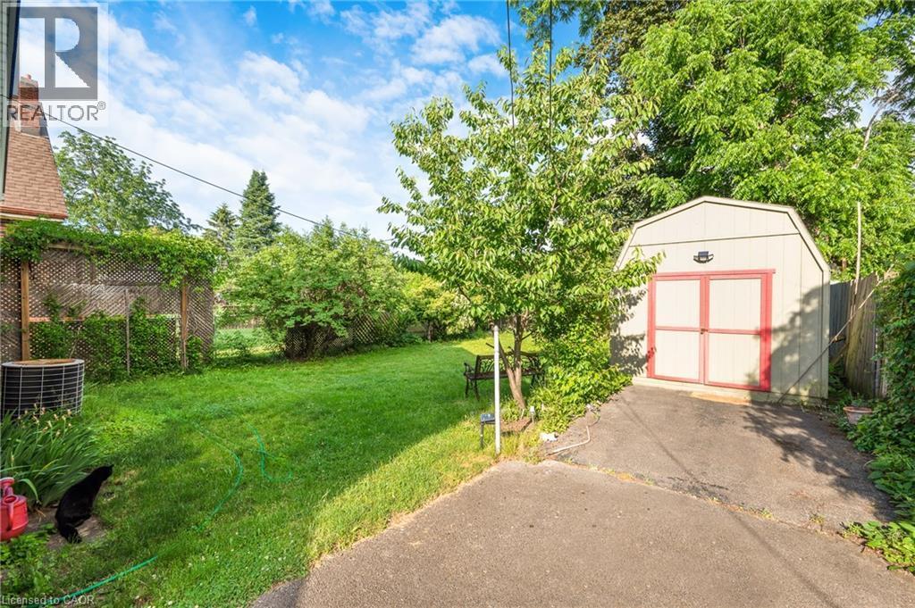 Expansive backyard with a manicured lawn, established trees, and a functional storage shed - 295 Keswick Court, Hamilton, ON