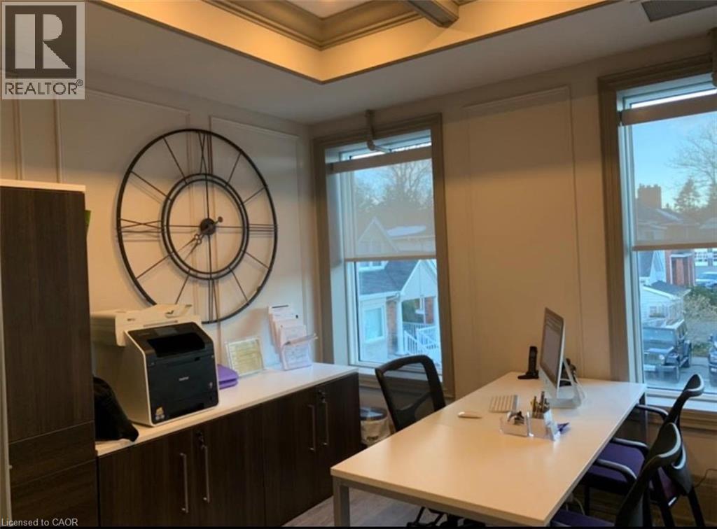 Dedicated office space featuring two large windows, built-in cabinetry with white countertops, and decorative wall paneling - 385 E Wilson Street E Unit# 201, Ancaster, ON