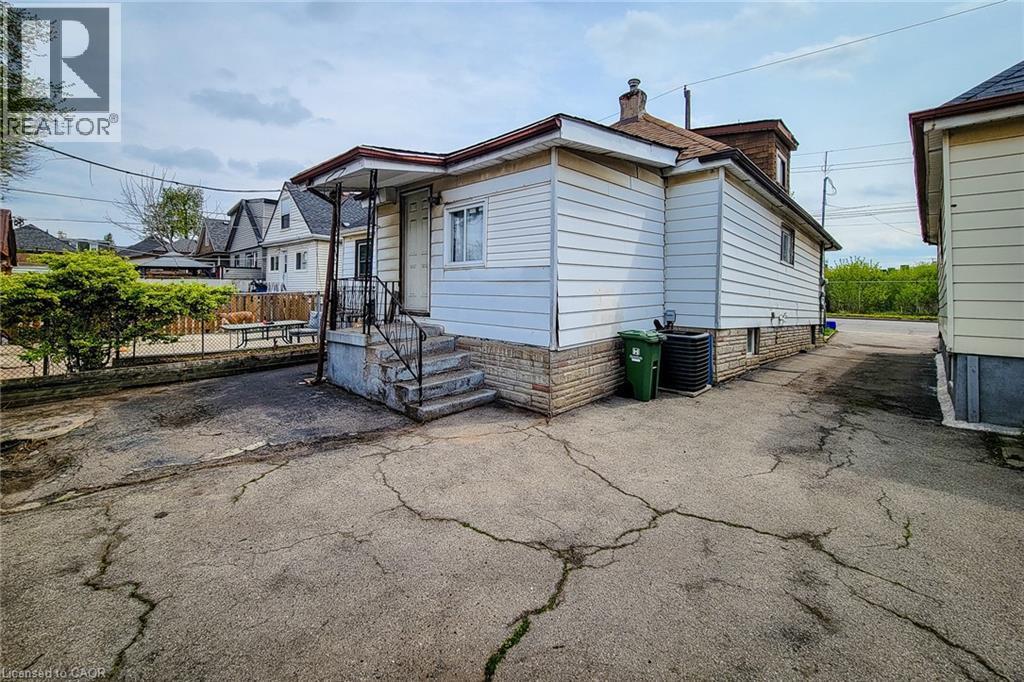 Rear exterior featuring white siding and a stone foundation - 463 Wellington Street N, Hamilton, ON - Outdoor