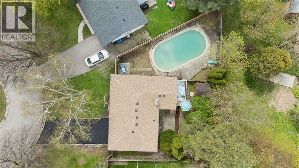 Oval in-ground swimming pool with surrounding concrete decking - 176 Woodville Place, Waterloo, ON - Outdoor With View