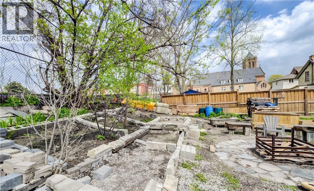 Spacious exterior area featuring a stone paver pathway, wood fencing, and mature trees - 46 Shanley Street, Kitchener, ON - Outdoor