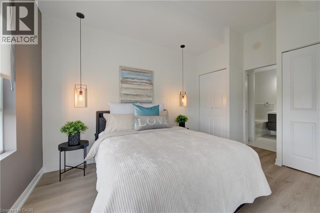 Bedroom featuring wood-finish flooring, two bi-fold closet doors, and recessed lighting - 191 King Street S Unit# 607, Waterloo, ON