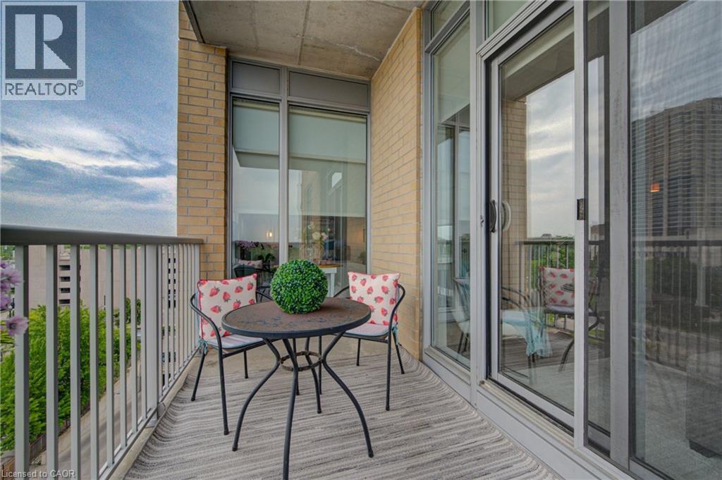 Private balcony featuring a light grey textured floor, painted metal railing, and brick exterior - 191 King Street S Unit# 607, Waterloo, ON