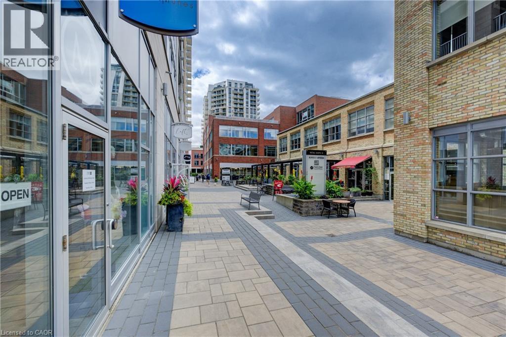 Paved courtyard featuring a variety of commercial storefronts with large glass windows and brick facades - 191 King Street S Unit# 607, Waterloo, ON