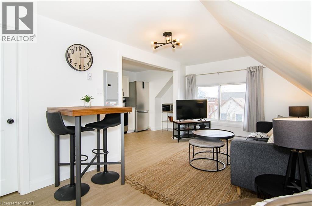 Open-concept living space featuring wood-finish flooring and a contemporary chandelier - 249 Emerald Street N, Hamilton, ON