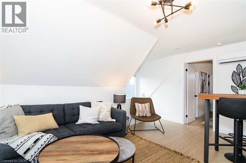 Attic space featuring sloped ceilings, light wood-finish flooring, and a modern multi-directional ceiling light fixture - 249 Emerald Street N, Hamilton, ON