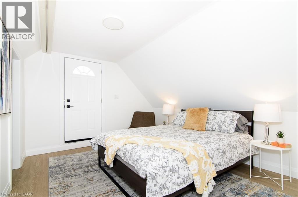Bright room featuring an arched paneled door, sloped ceiling, wood-finish flooring, and recessed lighting - 249 Emerald Street N, Hamilton, ON