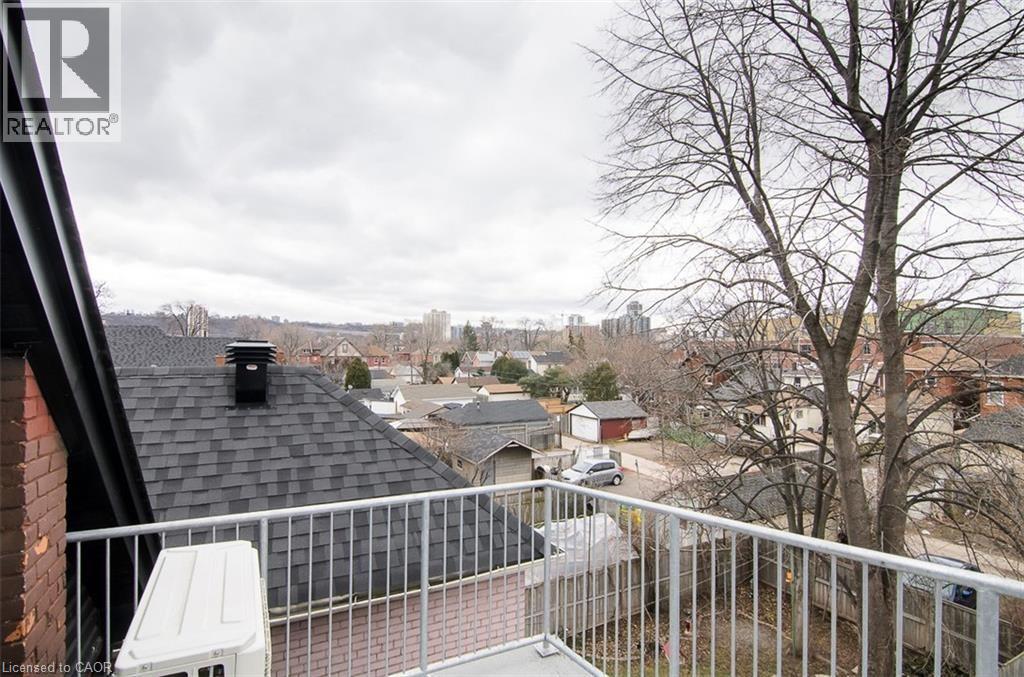 Balcony with metal railing offering elevated perspectives of the surrounding residential areas and distant structures - 249 Emerald Street N, Hamilton, ON