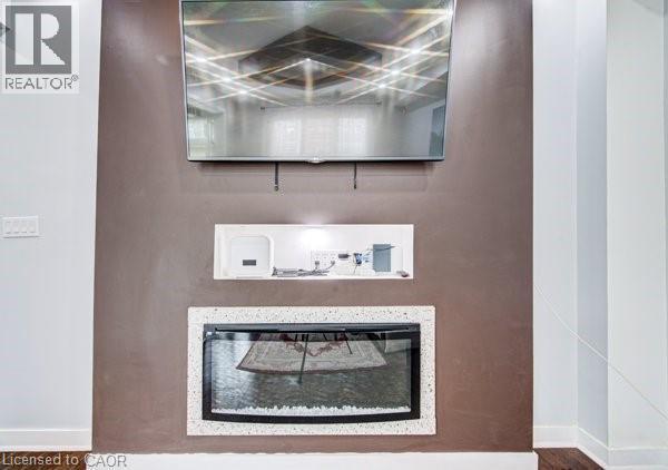 Built-in fireplace with a speckled white surround, integrated shelving with under-cabinet lighting, and a wall-mounted entertainment display above - 55 Isaiah Drive, Kitchener, ON