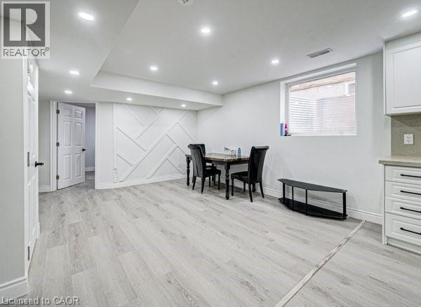 Spacious room featuring light wood-finish flooring, recessed lighting, and a decorative accent wall with geometric paneling - 55 Isaiah Drive, Kitchener, ON