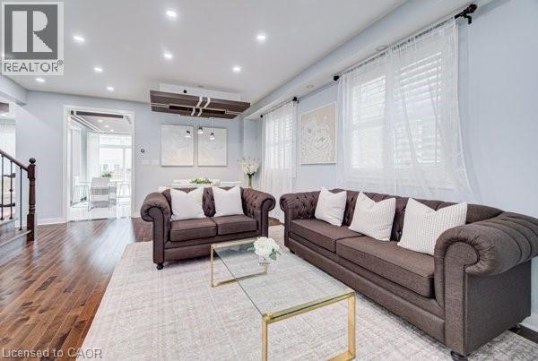 Spacious living area featuring wood-finish flooring, recessed lighting, and multiple windows with white blinds - 55 Isaiah Drive, Kitchener, ON