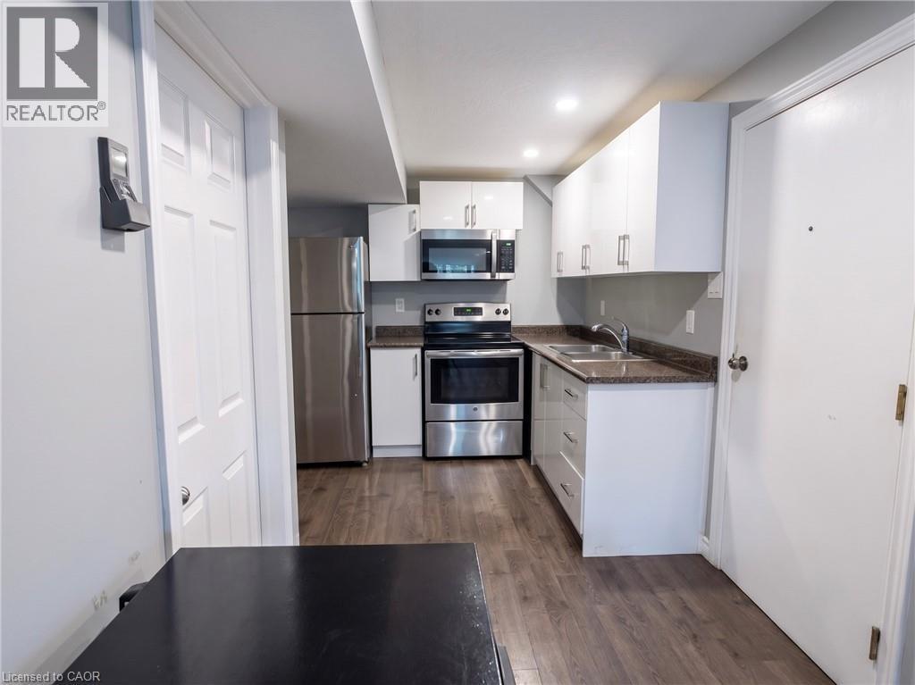 Kitchen featuring white cabinetry, stainless steel appliances, speckled countertops, and wood-finish flooring - 304 Lemon Grass Crescent Unit# B, Kitchener, ON