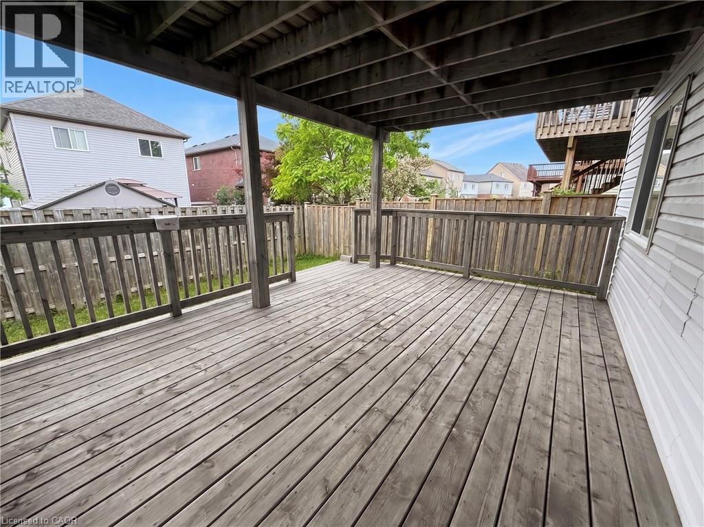 Expansive wood-plank deck featuring a full-height wood privacy fence, a covered overhead structure, and a partial view of a neighboring upper-level deck - 304 Lemon Grass Crescent Unit# B, Kitchener, ON