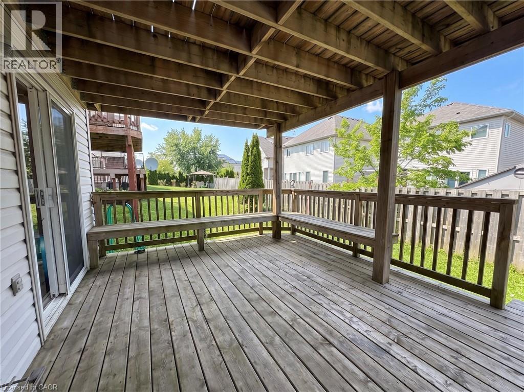 Spacious covered deck featuring built-in wooden benches, wooden railing, and a private backyard - 304 Lemon Grass Crescent Unit# B, Kitchener, ON
