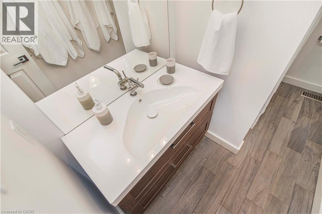 Bathroom vanity featuring a white countertop with an integrated sink, polished chrome faucet, and wood-finish cabinetry - 39 Forestgate Drive, Hamilton, ON