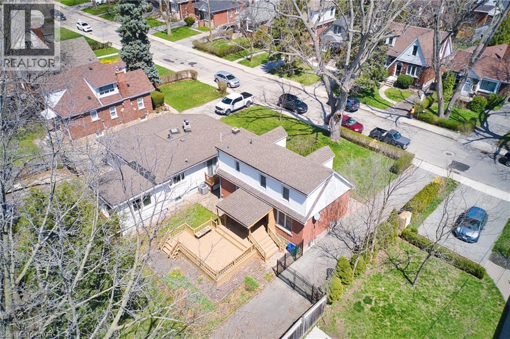 Two-story property featuring a multi-level deck, dark shingle roofing, and red brick lower exterior - 17 Thorndale Street N, Hamilton, ON