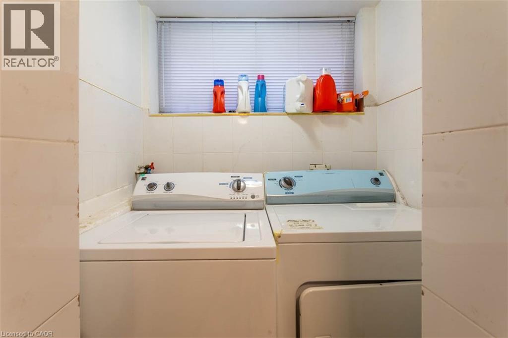 Laundry area featuring white ceramic wall tiling, a window with horizontal blinds, and a built-in shelf - 17 Thorndale Street N, Hamilton, ON