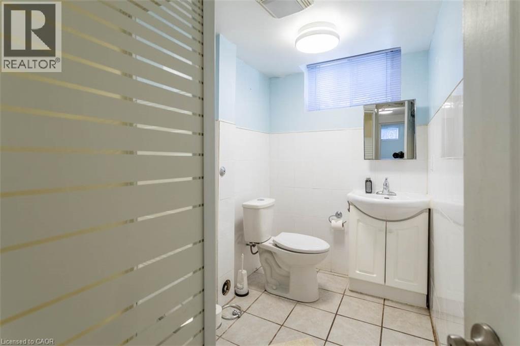 Bathroom featuring a vanity with a white cabinet and basin, a wall-mounted medicine cabinet, and a toilet - 17 Thorndale Street N, Hamilton, ON
